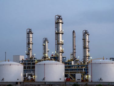 Industrial landscape of an oil refinery terminal at twilight, cool overcast lighting, sharp metallic structures and storage tanks, clean professional framing.