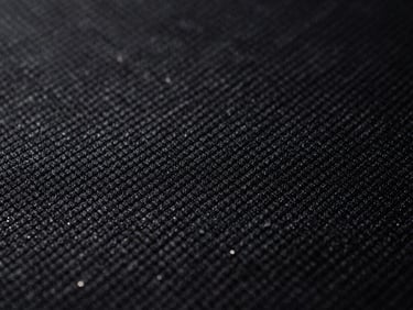 Macro detail shot of technical black athletic fabric weave, sharp highlights, dramatic studio lighting, 35mm film