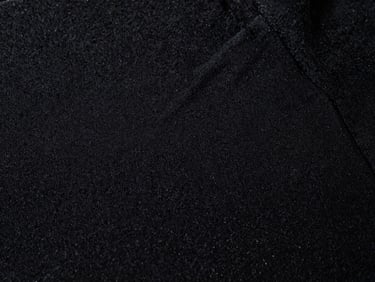 Extreme close-up of high-density embroidery on heavy black cotton fabric, dramatic side lighting, sharp highlights, 35mm film