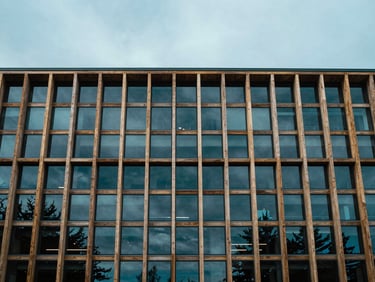 Wide shot of a modern architectural facade featuring natural timber and glass, under overcast Pacific daylight, cool blue tones, 35mm
