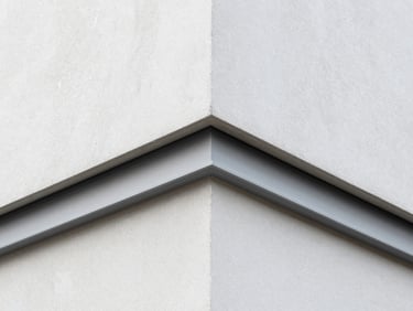Close-up of a perfectly sharp window frame angle on a modern plaster facade, clean silicone joints, precise execution.