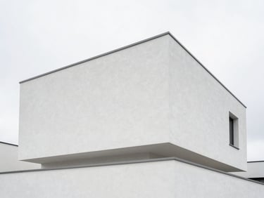 Minimalist modern Belgian villa exterior with a pristine white crépi facade, clean architectural angles, overcast sky.