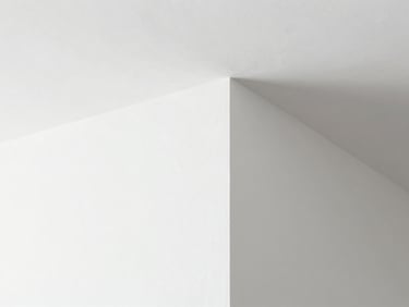 Architectural close-up of a perfectly smooth white Gyproc plaster joint, sharp corner bead, clean minimalist interior under bright natural light