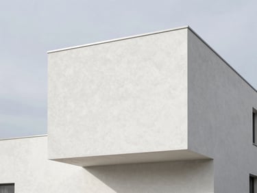 Minimalist modern house exterior showing flawless white crépi taloché texture against a soft Belgian sky, sharp shadow lines