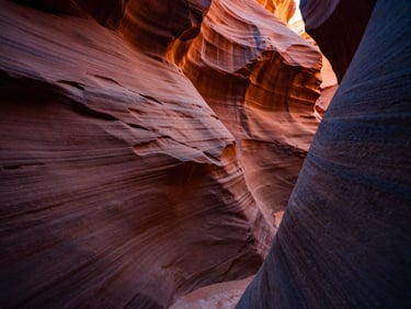 Close-up of textured red sandstone canyon walls glowing under warm golden hour light, deep shadows, cinematic travel photography
