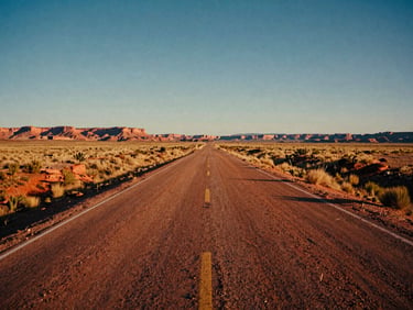 Wide cinematic shot of a dusty open road stretching straight to the horizon in Utah, dry grass on the side, warm midday sun casting long shadows, 35mm film look