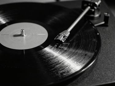 Extreme close-up of a spinning vinyl record in a dark studio, harsh key light reflecting off the grooves, gritty black and white, 35mm film.
