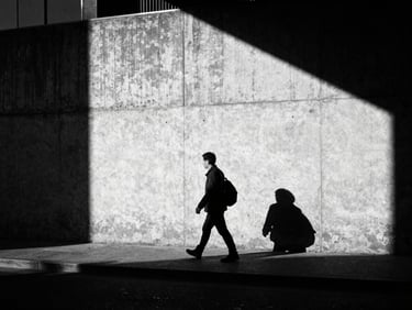 High-contrast street scene at night, a single figure walking past a glowing brutalist concrete wall, harsh shadows, heavy film grain.