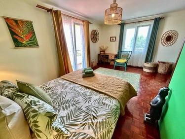 Tropical style bedroom featuring botanical bedding, bamboo decor, and a sunny balcony view.