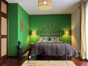 Tropical bedroom interior with green walls, rattan headboard, and warm boho lighting decor.