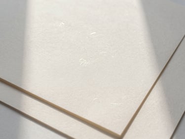 Overhead flat lay of layered heavy-weight cotton paper mockups, soft shadows, subtle pearlescent foil stamp details, diffused morning light