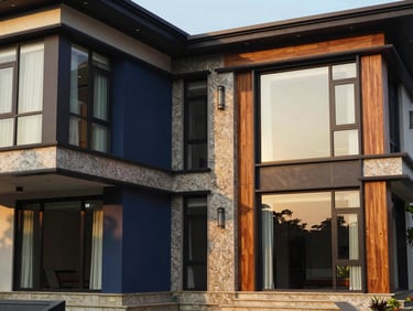 Architectural exterior photography of a modern luxury villa in Coimbatore, featuring premium granite and teak details, large glass windows reflecting golden-hour sunlight, sharp focus, 35mm