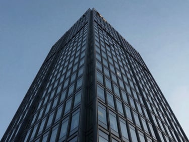 Dramatic low-angle perspective of a glass-and-steel commercial office tower, sharp geometric lines, blue hour lighting.