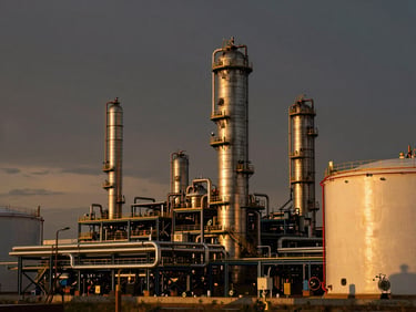 A clean modern petrochemical refinery plant under dramatic sunset sky, metallic pipes and storage tanks, high contrast