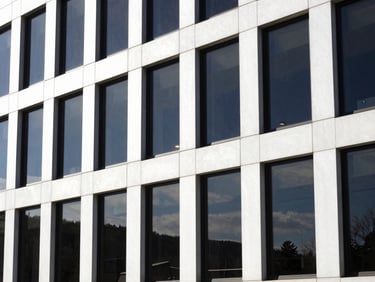 Exterior view of a modern office building with uniformly tinted windows, reflecting a crisp New Hampshire landscape, high-contrast.