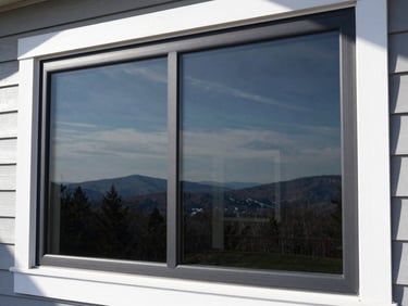 Modern home window with newly applied tinted film, reflecting a crisp New Hampshire landscape, high-contrast lighting.