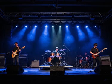 Wide shot of a live band performing on stage, drummer visible, electric blue stage lights, dynamic motion blur, low angle.