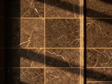 Straight-on architectural detail shot of perfectly aligned luxury marble tiles with gold grout accents, warm ambient light, sharp focus.