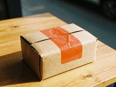 A candid close-up of a warm cardboard package with a vibrant orange sticker, sitting on a sunlit wooden table, cozy 35mm film style