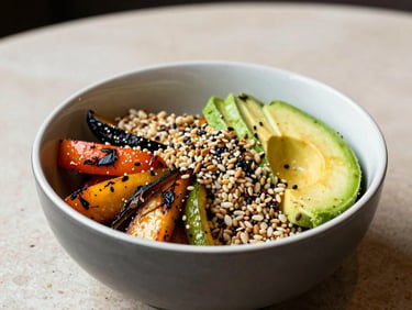 A vibrant organic grain bowl filled with roasted vegetables, avocado, and seeds in a sleek bowl on a light stone tabletop in a North American / US restaurant.