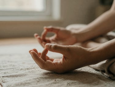 A close-up of hands resting in a quiet dhyana mudra on linen fabric, soft morning window light, warm earth tones, shallow depth of field.