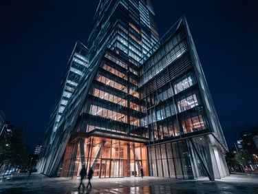 Wide-angle architectural perspective of a modern steel and glass commercial structure, sharp geometric shadows, cool blue low-key lighting with warm copper reflections, 35mm.
