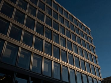 Low-angle dramatic architectural shot of a modern federal court glass facade reflecting a dark blue sky, sharp lines, 35mm