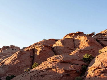 Bright natural morning light on rugged red rock cliffs of Manila Utah, wide 21:9 panoramic framing, negative space on the left, clean editorial style