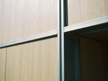 Macro architectural detail of grain-matched oak paneling meeting a cold-rolled steel frame, sharp natural daylight, 35mm film style.