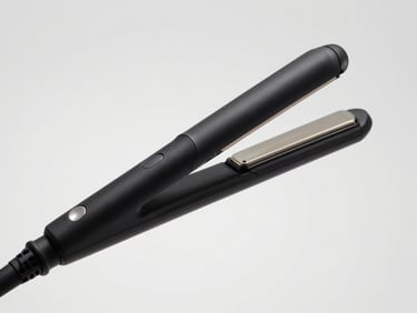 High-key studio shot of a minimalist matte black hair straightener, seamless warm-gray background, sharp focus, 50mm lens
