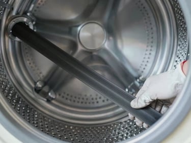 Macro shot of a clean metal washing machine drum belt being tensioned by a gloved technician, bright cool LED light.
