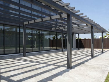 Modern steel pergola projecting sharp geometric linear shadows on a concrete terrace, bright daylight.