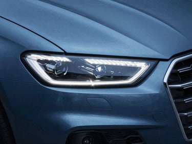 A modern luxury car headlight and grille, cool blue ambient light, sharp metallic reflections.