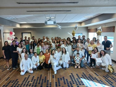 A large group of people posing for a group photo at a celebratory event in a conference room.