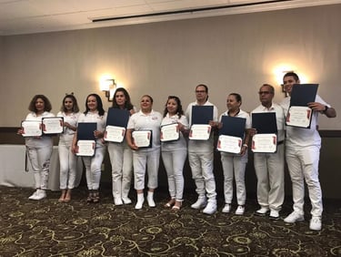 A group of diverse professionals in white uniforms holding graduation certificates and award folders.