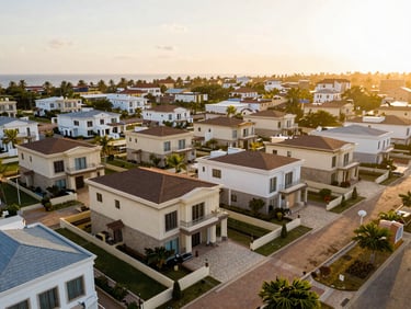 Aerial view of a premium residential plot in Fidjrossè Cotonou, close to the beach, warm golden sunlight, clean boundary lines, luxury villas in the background