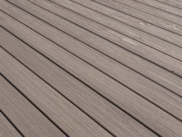 Overhead architectural shot of composite outdoor decking boards, warm grey-brown grain texture, precise plank alignment and uniform gap spacing, controlled daylight, no people, empty terrace surface