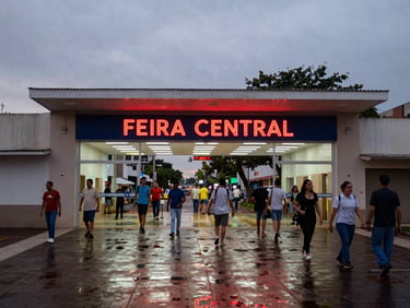Wide shot of the entrance of Feira Central in Campo Grande at dusk, neon signs reflecting on wet pavement, active street scene, candid 35mm photography