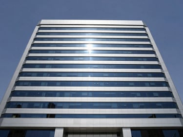 Wide-angle architectural shot of a modern corporate headquarters in Riyadh, high-contrast daylight, clean silver and deep navy tones, professional and authoritative