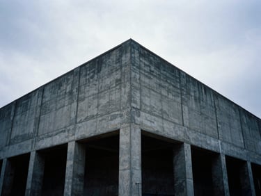 Low-angle heroic framing of a massive concrete foundation poured for an industrial warehouse, cool overcast daylight, 35mm film