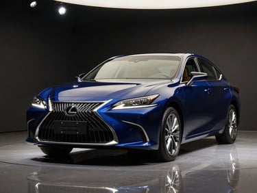 Close three-quarter front of a deep blue Lexus ES 350 inside a dark showroom, single overhead spotlight illuminating the spindle grille, polished floor reflection below