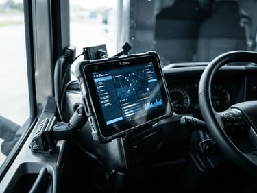 Close-up of a rugged tablet displaying logistics software inside a modern freight truck cabin, industrial steel tones, daylight.
