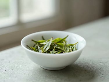 A minimalist white ceramic bowl with organic green tea leaves, soft natural light, shallow depth of field, 35mm