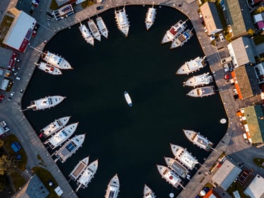 Directly overhead nadir drone shot of a colorful harbor market with symmetric docks and boats, golden hour light