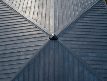 Directly overhead nadir drone shot of a modern metal roof, perfect geometric lines, soft overcast daylight