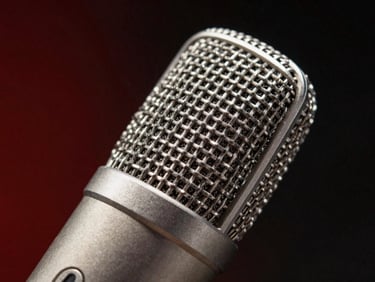 Studio microphone capsule close-up, metallic texture, dark background with subtle red recording glow.