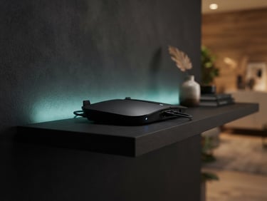 Sleek modern black router hardware on a dark minimalist shelf, soft teal ambient light glow from behind, sharp focus, clean tech aesthetic