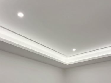 Environmental shot of a completed false ceiling installation with recessed LED lighting, geometric plaster details, photographed looking upward in an empty room, clean white finish, even diffused illumination