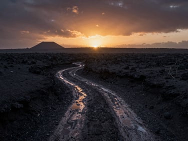 Plano general cinematográfico de una llanura volcánica oscura bajo un cielo crepuscular denso, reflejos mínimos de luz en senderos húmedos.