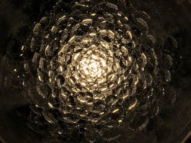 Abstract macro shot of light reflecting off textured dark glass, golden glints, mysterious and poetic